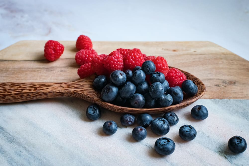 Blueberries and raspberries served on a wooden spoon
