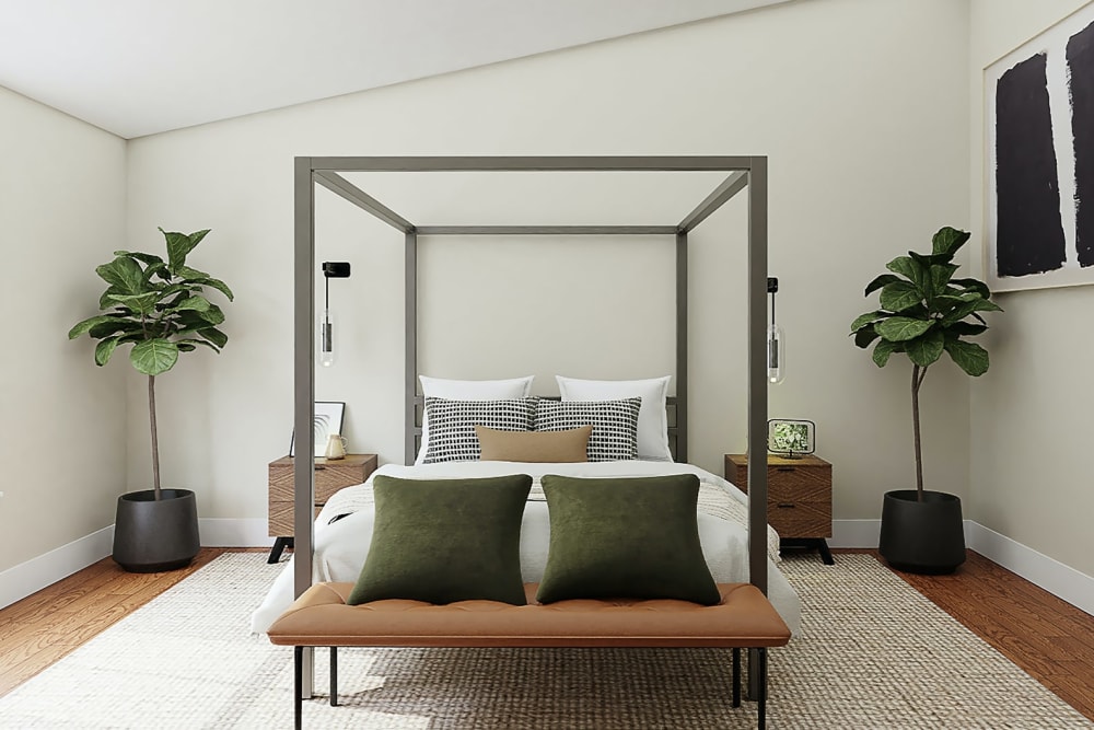 Two medium sized fiddle leaf fig plants stand either side of a four poster bed.