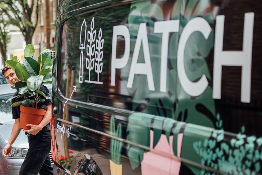 Member of Patch staff delivering a plant and a Patch delivery van